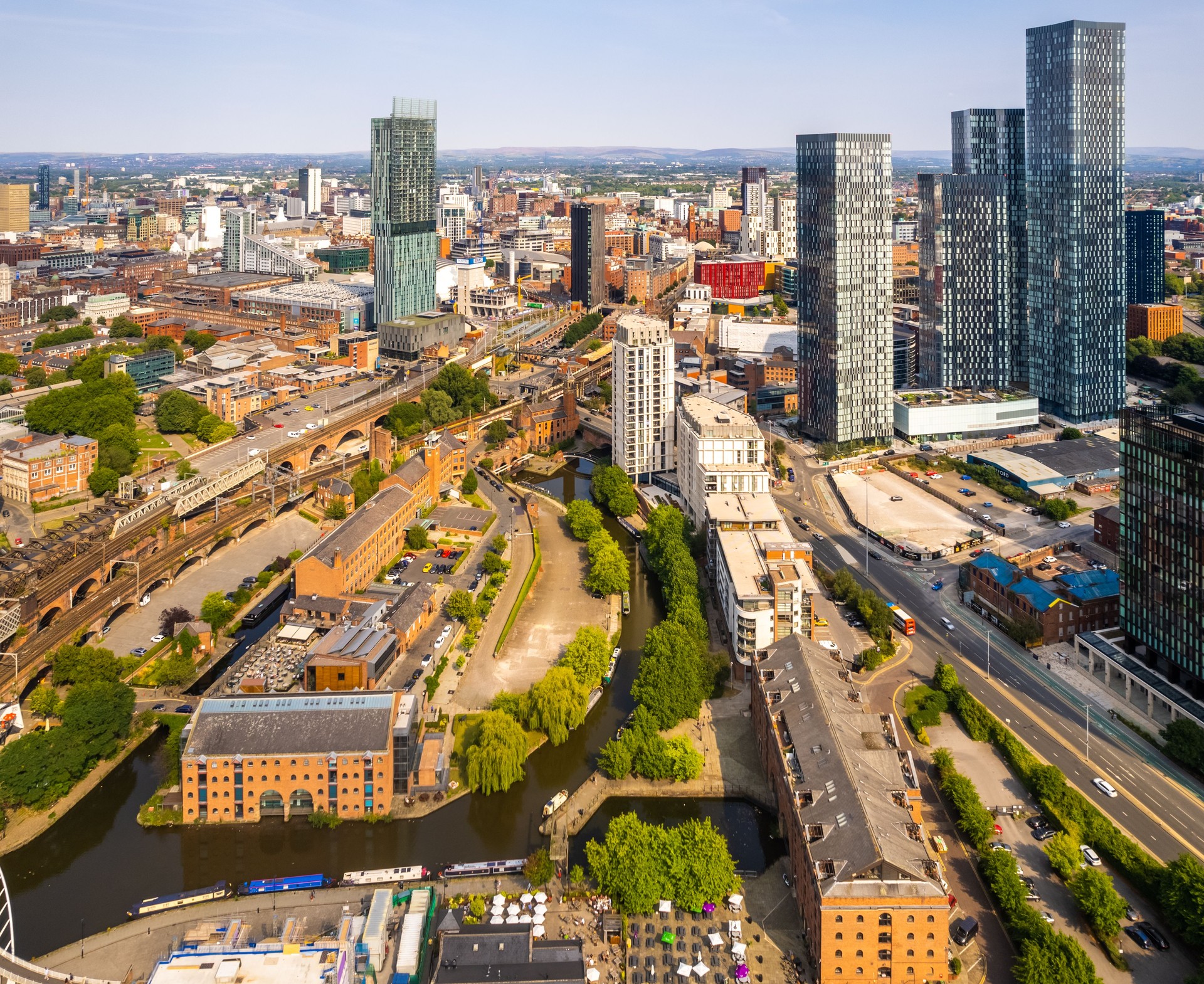 Manchester United Kingdom aerial shot of modern buildings with lots of counstruction in the central area of the city with historic canals in the foreground